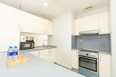 a kitchen with white cabinets and a stove top oven at PVH - Sunny Studio near Metro - Madison Residency in Dubai
