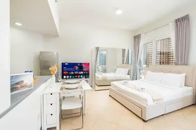 a white bedroom with a bed and a desk with a computer at PVH - Sunny Studio near Metro - Madison Residency in Dubai