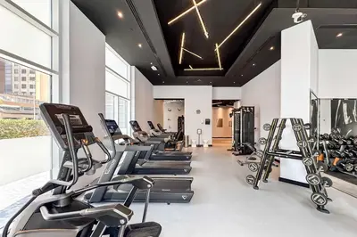 a gym with a row of treadmills and ellipticals at PVH - Sunny Studio near Metro - Madison Residency in Dubai
