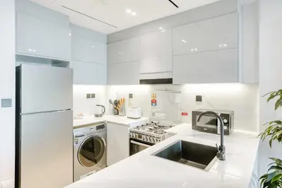 a white kitchen with a sink and a dishwasher at PVH - Exquisite 1BR With Canal View - Binghatti Canal, Business Bay in Dubai