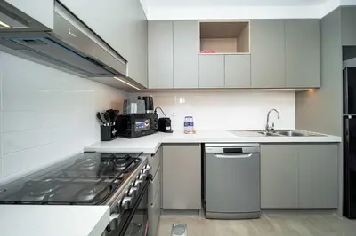 a white kitchen with a sink and a stove at PVH - Creek Gate - Stylish 2BR with Creek View in Dubai