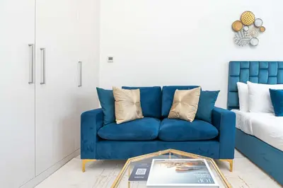 a blue couch in a living room with a table at PVH - Classy Studio with Golf Course View - Carson in Dubai