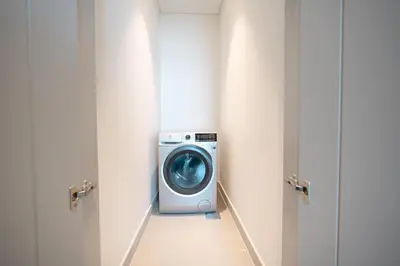 a washing machine in a laundry room with two doors at PVH - Forte Tower 1 - Opulent 2BR near Dubai Mall in Dubai