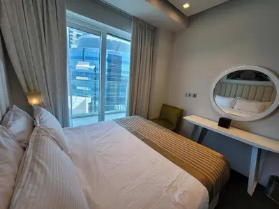 a bedroom with a bed and a mirror and a window at Damac Heights - Blue Ocean Holiday Homes in Dubai
