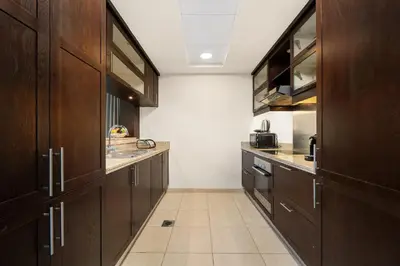 a kitchen with wooden cabinets and a tiled floor at Downtown Gem, 1 BDR Apartment, Walk to Dubai Mall & Burj khalifa in Dubai