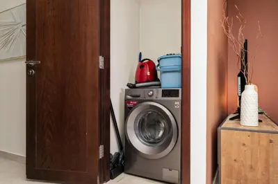 a washing machine in a room next to a door at Downtown Gem, 1 BDR Apartment, Walk to Dubai Mall & Burj khalifa in Dubai