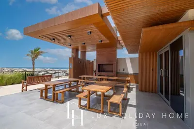 a house with wooden tables and benches on a patio at LUX The Le Pont Sea View Suite in Dubai