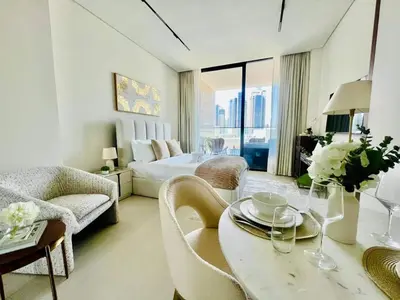 a white living room with a bed and a table at Business Bay Studio Jacuzzi & Iconic View in Dubai