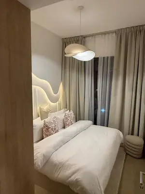 a bedroom with a large white bed with a light at Appartement moderne et élégant in Dubai