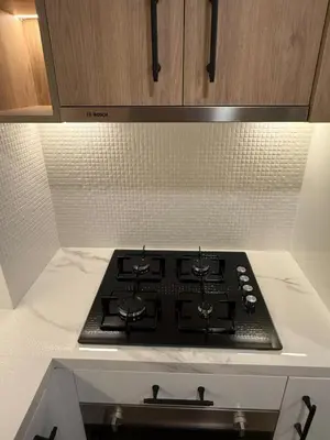 a black stove top in a kitchen with cabinets at Appartement moderne et élégant in Dubai