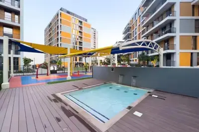 a swimming pool with a blue and yellow umbrella at Peaceful Studio Midtown 20 mins to Expo City by Vibel in Dubai