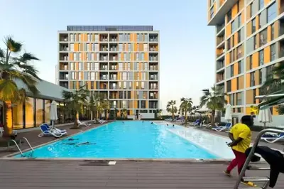 a person walking by a swimming pool in a resort at Peaceful Studio Midtown 20 mins to Expo City by Vibel in Dubai