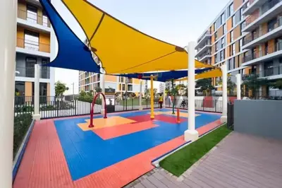 a playground with a large yellow and blue umbrella at Peaceful Studio Midtown 20 mins to Expo City by Vibel in Dubai
