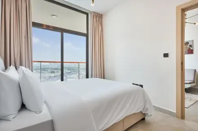 a bedroom with a white bed and a large window at One Bedroom Apartment in Binghatti Avenue by The S Holiday Homes in Dubai