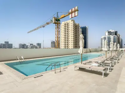 a swimming pool on top of a building with a crane at Silkhaus New 1BDR Retreat at Binghatti Tulip in JVC in Dubai