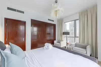a bedroom with a large white bed and a window at Burj and Fountain view 3BR plus maids room in Dubai