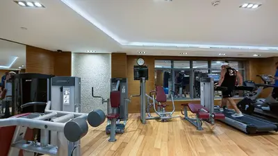 a woman walking through a gym with exercise equipment at Modern 1BR in Avanti with Pool & Gym in Dubai