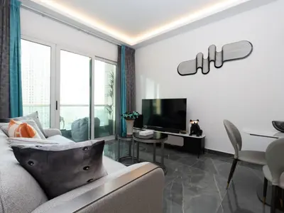 a living room with a couch and a table and a television at Cozy and Uniquely Furnished One Bedroom Dubai Marina in Dubai