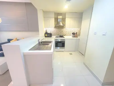 a kitchen with white cabinets and a sink at Damac Voleo - Blue Ocean Holiday Homes in Dubai