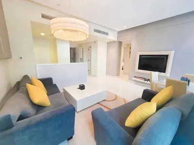 a living room with a blue couch and a tv at Damac Voleo - Blue Ocean Holiday Homes in Dubai