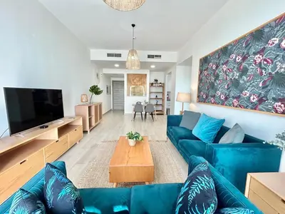 a living room with a blue couch and a table at Homes2Retreat - Luxury Finishes with Full Skyline View in Dubai