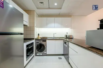 a kitchen with white cabinets and a washer and dryer at Luxury Escapes- Elegant Marina View Bay Central 3BR and Maids Room- single bed in Dubai
