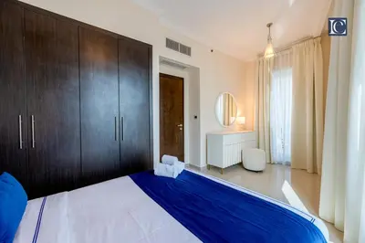 a bedroom with a large bed with blue sheets and wooden cabinets at Luxury Escapes- Elegant Marina View Bay Central 3BR and Maids Room- single bed in Dubai