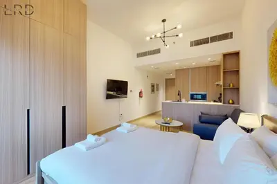 a bedroom with a white bed and a living room at Brand New and Modern Studio Apartment in Dubai