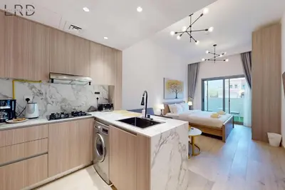 a kitchen and living room with a bed in the background at Brand New and Modern Studio Apartment in Dubai