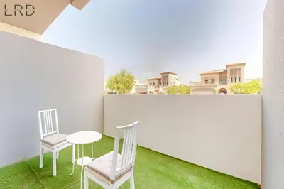 two chairs and a table on a balcony with grass at Brand New and Modern Studio Apartment in Dubai