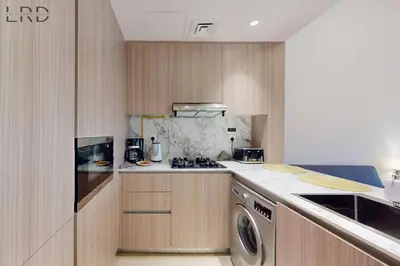 a kitchen with a stove and a washer at Brand New and Modern Studio Apartment in Dubai