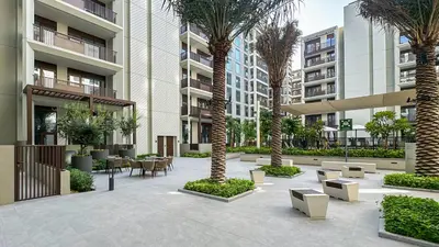 a courtyard with palm trees and tables and benches at Resort-Style 1BR in Dubai Creek Harbour -1AB01 in Dubai