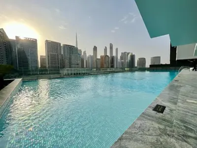 a large swimming pool with a city in the background at Studio With Jaw-Dropping Canal And Burj Views in Dubai