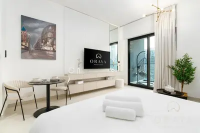 a white bedroom with a dining table and a bed at Studio With Jaw-Dropping Canal And Burj Views in Dubai