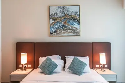 a bedroom with a bed with two lamps and a painting at Bright & Elegant Saven The Palm 1bhk Apartment in Dubai