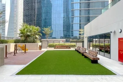a park with benches and grass in a building at CasaHue - Canal x Burj View - 4Guest - Award Winning in Dubai
