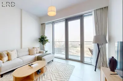 a living room with a white couch and large windows at Elegant 2BR with Maids and Stunning Canal Views in Dubai