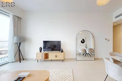 a living room with a tv and a mirror at Elegant 2BR with Maids and Stunning Canal Views in Dubai