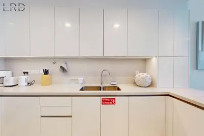 a kitchen with white cabinets and a sink at Elegant 2BR with Maids and Stunning Canal Views in Dubai