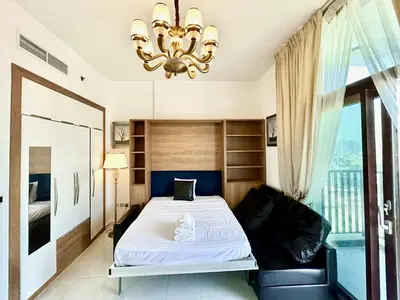 a bedroom with a bed and a chandelier at Homes2Retreat - Glamz Haven Stylish Studio with Balcony in Dubai