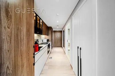 a kitchen with white counters and wooden cabinets at Hamilton House, Jumeirah Village Circle in Dubai