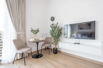 a living room with a table and chairs and a tv at New Studio Close to Town Square Park, Short Drive to Al Qudra Lake, Liva Apartments by Deluxe Holiday Homes in Dubai