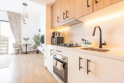 a kitchen with white cabinets and a sink at New Studio Close to Town Square Park, Short Drive to Al Qudra Lake, Liva Apartments by Deluxe Holiday Homes in Dubai
