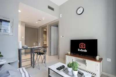 a living room with a tv on a white wall at Stylish 1BR Close to Metro Burj Khalifa & Dubai Canal in Dubai