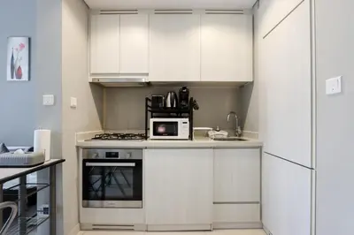 a kitchen with white cabinets and a microwave on a counter at Stylish 1BR Close to Metro Burj Khalifa & Dubai Canal in Dubai