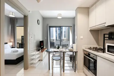 a kitchen and living room with a bed and a table at Stylish 1BR Close to Metro Burj Khalifa & Dubai Canal in Dubai