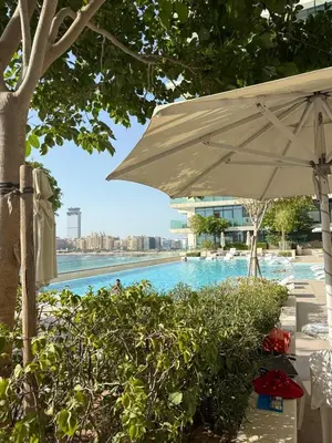 an umbrella next to a swimming pool with a building at Blue Horizon Living in Dubai