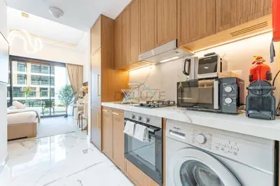 a kitchen with a washing machine and a microwave at Pool and Community View Studio, Near Top Landmarks, Azizi Riviera 59, Al Merkadh by Deluxe Holiday Homes in Dubai
