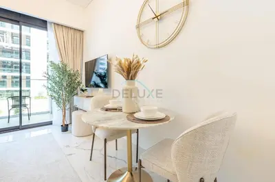 a dining room with a table and chairs and a clock on the wall at Pool and Community View Studio, Near Top Landmarks, Azizi Riviera 59, Al Merkadh by Deluxe Holiday Homes in Dubai