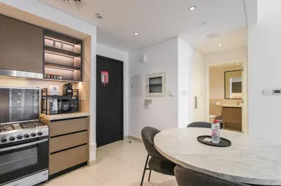 a kitchen with a table with chairs and a counter top at High-Rise & Boulevard View - 5-min to Burj & Mall in Dubai